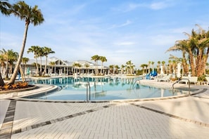 Uma área de piscina com espreguiçadeiras e palmeiras.