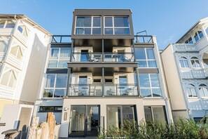 Ein mehrstöckiges Gebäude mit einem Balkon im zweiten Stock, großen Fenstern und einer Tür mit einer Nummer.