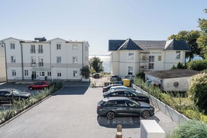 A parking area with multiple cars, a building with a sign 'SEEROSE', and a view of the sea in the background. - Ostseeglück Sassnitz - Stylish Apartment by the Sea (Sassnitz)