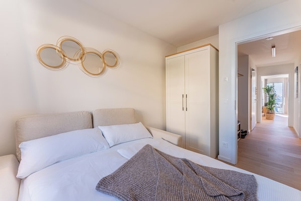 Ein Schlafzimmer mit einem Bett, einem Kleiderschrank und einem an der Wand befestigten Spiegel.