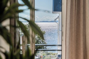 A view of a body of water with mountains in the distance, seen through a window with curtains. - Ostseeglück Sassnitz - Stylish Apartment by the Sea (Sassnitz)