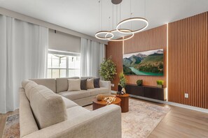 A modern living room with a sectional sofa, a coffee table, a large flat-screen TV, and a wooden accent wall. - 4 BD/ 3 BA/ Storey Lake (4796 CT) (Kissimmee)