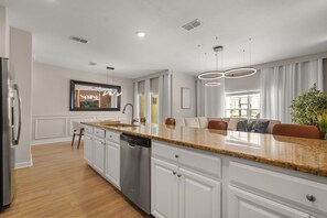 A modern kitchen with white cabinetry, a granite countertop, and a built-in dishwasher. - 4 BD/ 3 BA/ Storey Lake (4796 CT) (Kissimmee)