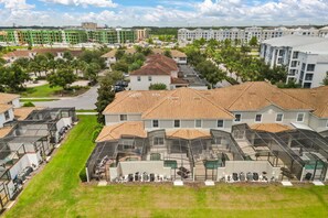 A residential area with multiple houses, some with sloped roofs and others with flat roofs, surrounded by greenery and a clear sky. - 4 BD/ 3 BA/ Storey Lake (4796 CT) (Kissimmee)