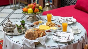 En morgenmadsopstilling med skåle med frugt, brød, æg og juice på et bord.