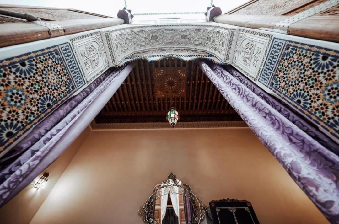 An ornate room with a high ceiling, intricate tile work, and a chandelier.