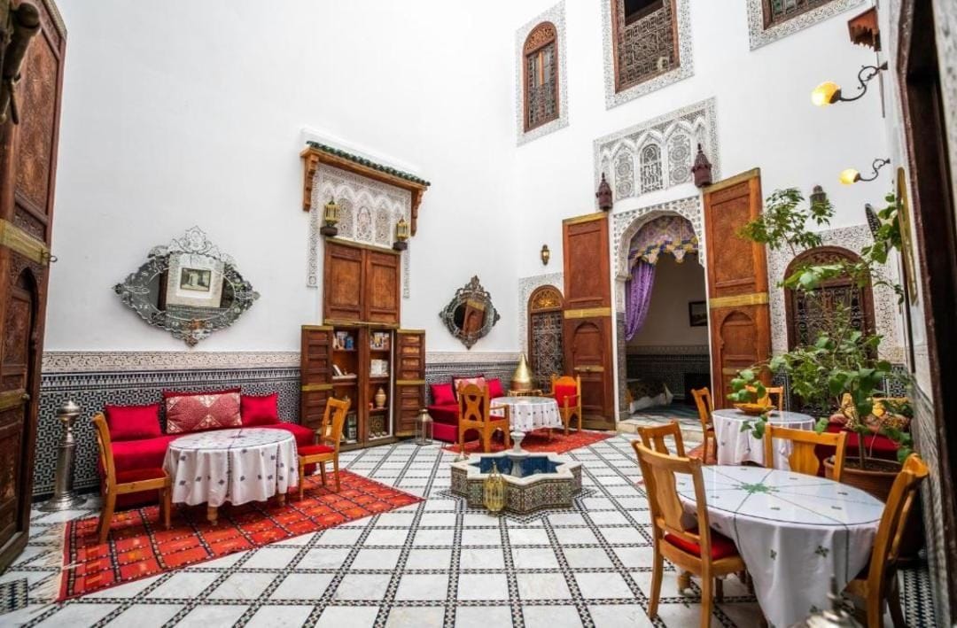 A traditional Moroccan interior with a tiled floor, wooden furniture, and ornate doors.