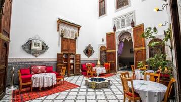 A traditional Moroccan interior with a tiled floor, wooden furniture, and ornate doors.