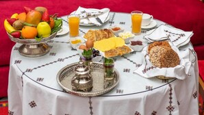Une table de petit-déjeuner avec une variété d’aliments et de boissons, notamment des fruits, du pain et une théière.