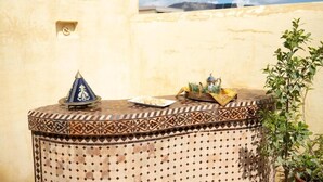 Une table ronde ornée d’un motif de carreaux, une lampe décorative et un plateau contenant divers objets.