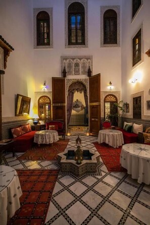 Un interior tradicional con un arco central, varias zonas de estar y un suelo estampado.