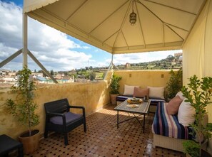 Un espacio de estar al aire libre techado con una mesa, sillas y un sofá.