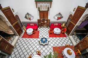 A room with a checkered floor, two red sofas, a central fountain, and traditional decor. - Riad Arabella  (Fes)