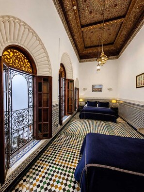 Una habitación con piso a cuadros, cama con cubrecama azul y techo estampado.