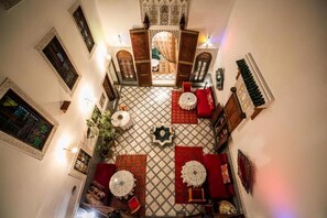 Una habitación con piso a cuadros, muebles rojos y blancos, y decoraciones ornamentales en las paredes.