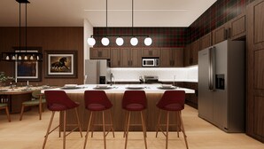 Una cocina moderna con una isla central, taburetes de bar, microondas y refrigerador.