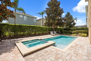 A rectangular swimming pool with a hot tub, surrounded by a brick patio, and bordered by a hedge. - Cinematic 6 BD/ 6.5 BA/ Encore Resort at Reunion - 480 LD (Kissimmee)