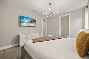 A bedroom with a bed, a dresser, a television mounted on the wall, and a ceiling light fixture. - Cinematic 6 BD/ 6.5 BA/ Encore Resort at Reunion - 480 LD (Kissimmee)
