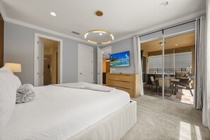 Een hotelkamer met een groot bed, een houten dressoir, een flatscreen televisie en een balkon met een eettafel.