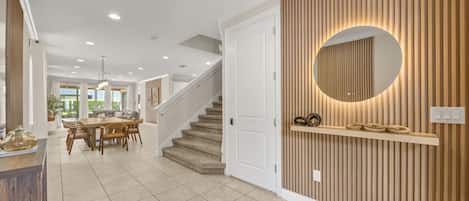 Ein modernes Interieur mit Treppe, Essbereich und einem wandmontierten Spiegel.
