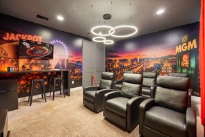 A room with a gaming theme, featuring a roulette wheel, blackjack table, and a cityscape mural. - Cinematic 6 BD/ 6.5 BA/ Encore Resort at Reunion - 480 LD (Kissimmee)