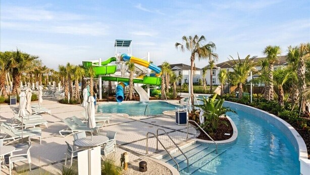 Ein Poolbereich mit Wasserrutsche, Liegestühlen und Palmen.