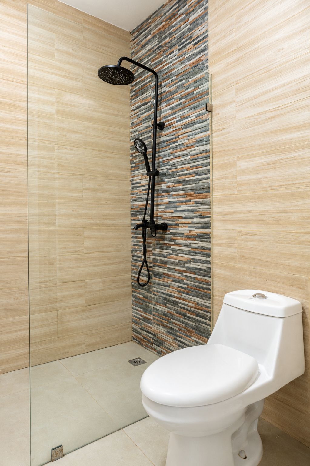 A bathroom with a shower, a toilet, and a wall with a patterned design.