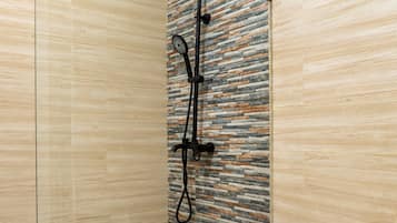 A bathroom with a shower, a toilet, and a wall with a patterned design.