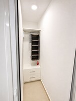 Un couloir étroit avec un placard blanc contenant des étagères et une tringle à vêtements.