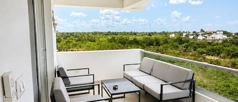 Ein Balkon mit Deckenventilator, einer Couch und zwei Stühlen.
