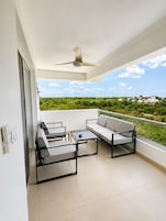 Un balcon avec un ventilateur de plafond, un canapé et deux fauteuils.