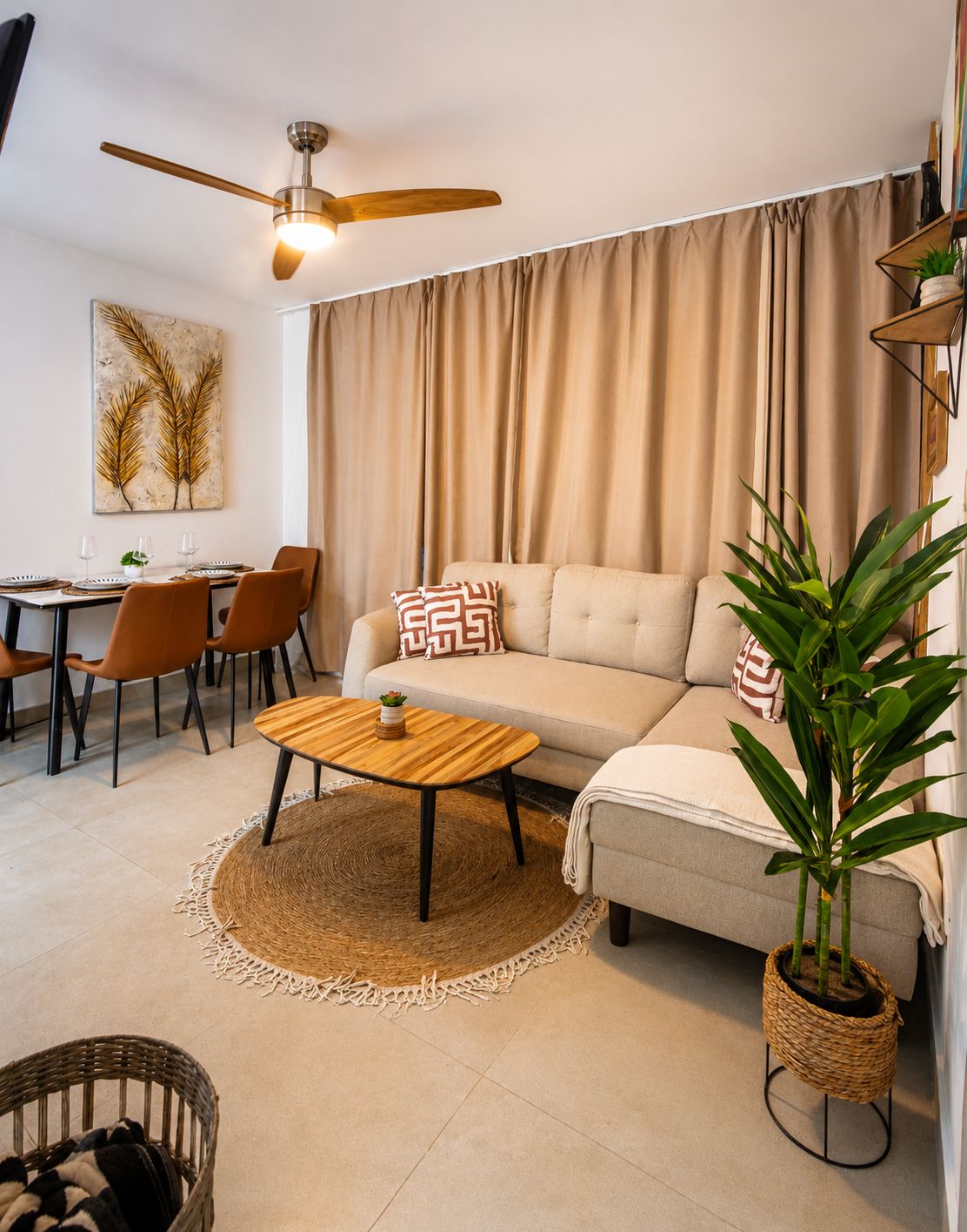 A living room with a sofa, a coffee table, a dining table with chairs, a ceiling fan, and a large window with curtains.