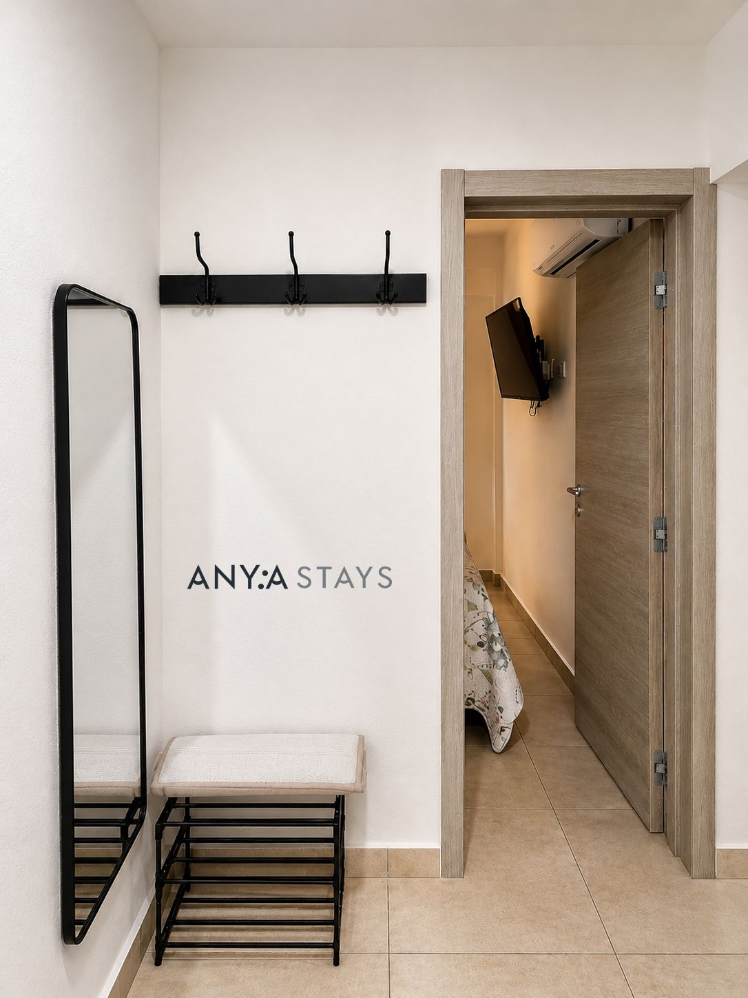 Un pasillo con un banco, perchero y una puerta que da a una habitación.