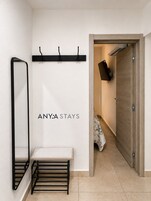Un pasillo con un banco, perchero y una puerta que da a una habitación.