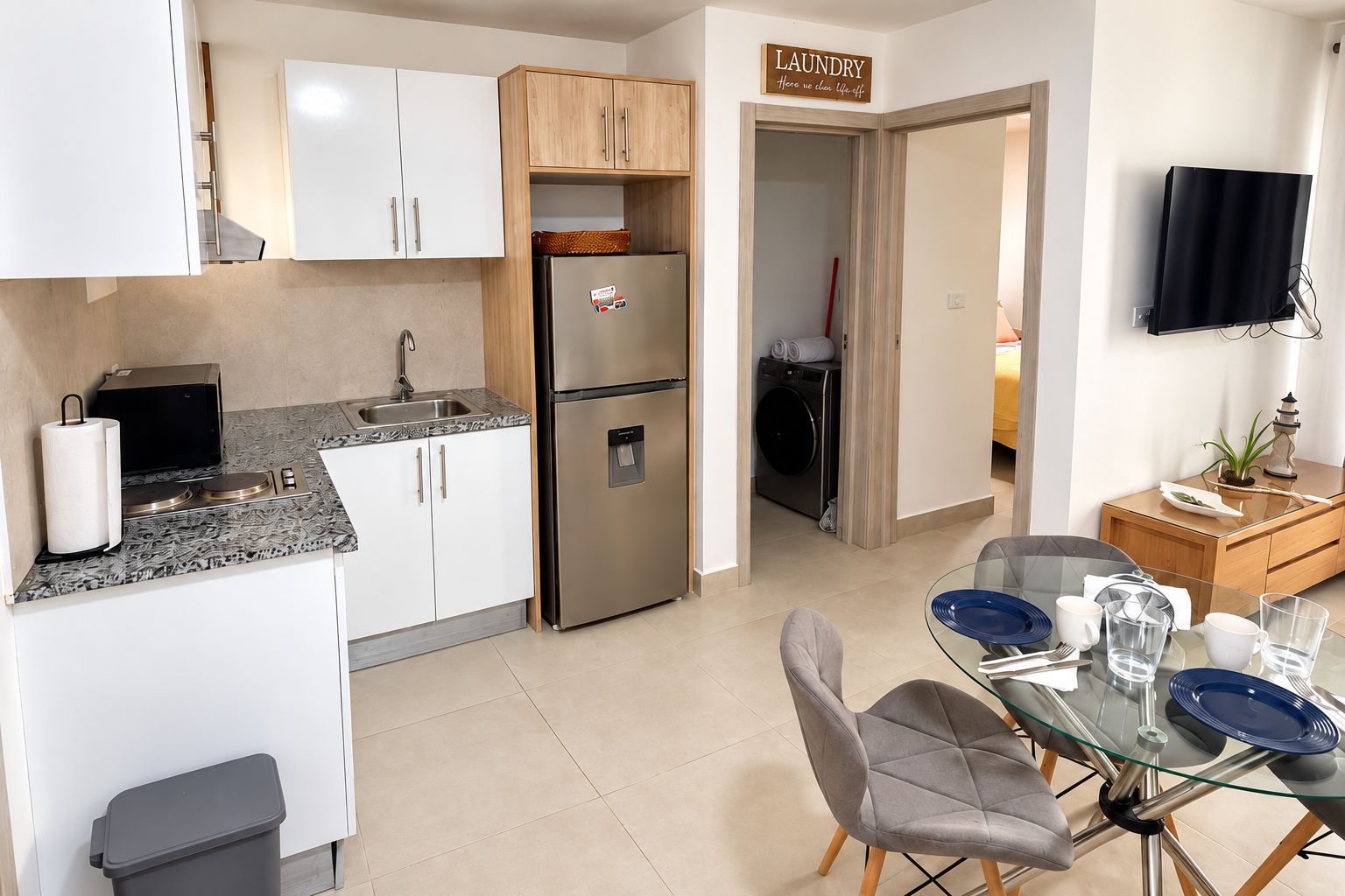 A compact kitchen with a refrigerator, stove, and a dining area with a glass table and chairs.