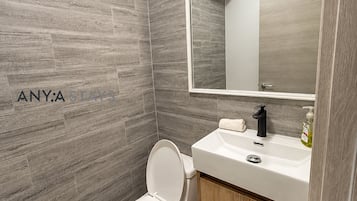 Une salle de bain moderne avec des toilettes, un lavabo et un miroir.
