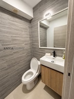 Un baño moderno con inodoro, lavabo y espejo.