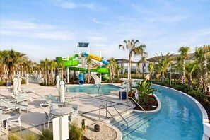 A pool area with a water slide, lounge chairs, and palm trees. - 10 BD/ 8 BA/ Windsor Cay (16224 SM) (Clermont)