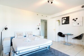A modern bedroom with a bed, bedside tables, a desk, and chairs. - Le Studio du Park avec terrasse et garage (Cannes)