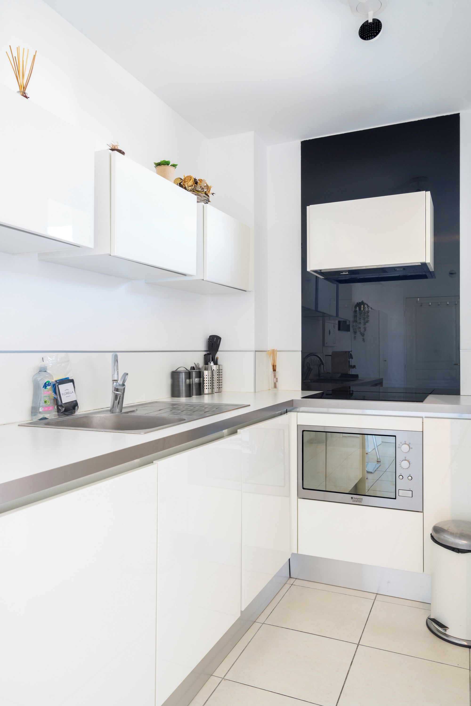 A modern kitchen with white cabinetry, a built-in oven, and a stainless steel sink.