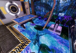 A pool table with a futuristic design, surrounded by a forest-themed environment with artificial foliage and a large speaker system. - 10 BD/ 8 BA/ Windsor Cay (15866 CK) (Clermont)