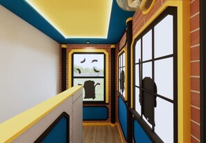 Un couloir étroit avec un mur en briques, une fenêtre donnant sur un paysage et une porte dotée d’une poignée noire.