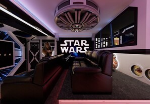 A room with a Star Wars theme, including a large illuminated sign, a sofa, and a wall with circular designs. - 10 BD/ 8 BA/ Windsor Cay (15866 CK) (Clermont)