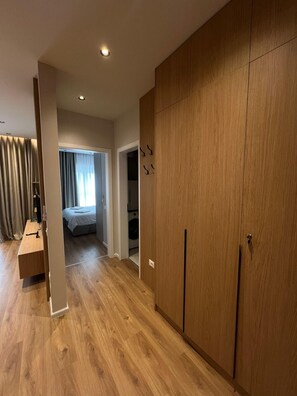 A room with a wooden wardrobe, a bed, a desk, and a washing machine. - SkyNest by the Lake @30 min to centre, AC and Balcony (Tiranë)