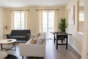 A living room with a sofa, a coffee table, and a foosball table. - Spacious 5 Bedroom House close to Strip, Airport, Stadium, Shopping, and Arena (Las Vegas)