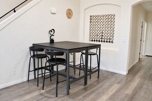A dining area with a table and four chairs, a wall-mounted clock, and a decorative circular pattern. - Spacious 5 Bedroom House close to Strip, Airport, Stadium, Shopping, and Arena (Las Vegas)
