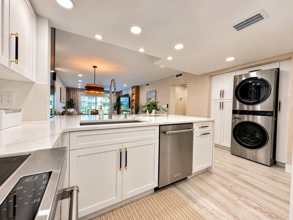 Una cocina moderna con muebles blancos, electrodomésticos de acero inoxidable y lavavajillas integrado.