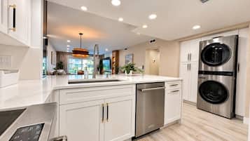 Una cocina moderna con muebles blancos, electrodomésticos de acero inoxidable y lavavajillas integrado.