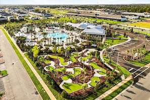 Vista aérea de um resort com piscina, áreas ajardinadas e estacionamento.