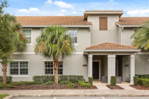 A two-story building with a tiled roof, a covered entrance, and numbered doors. - 4 BD/ 3 BA/ Storey Lake (4887 RC) (Kissimmee)